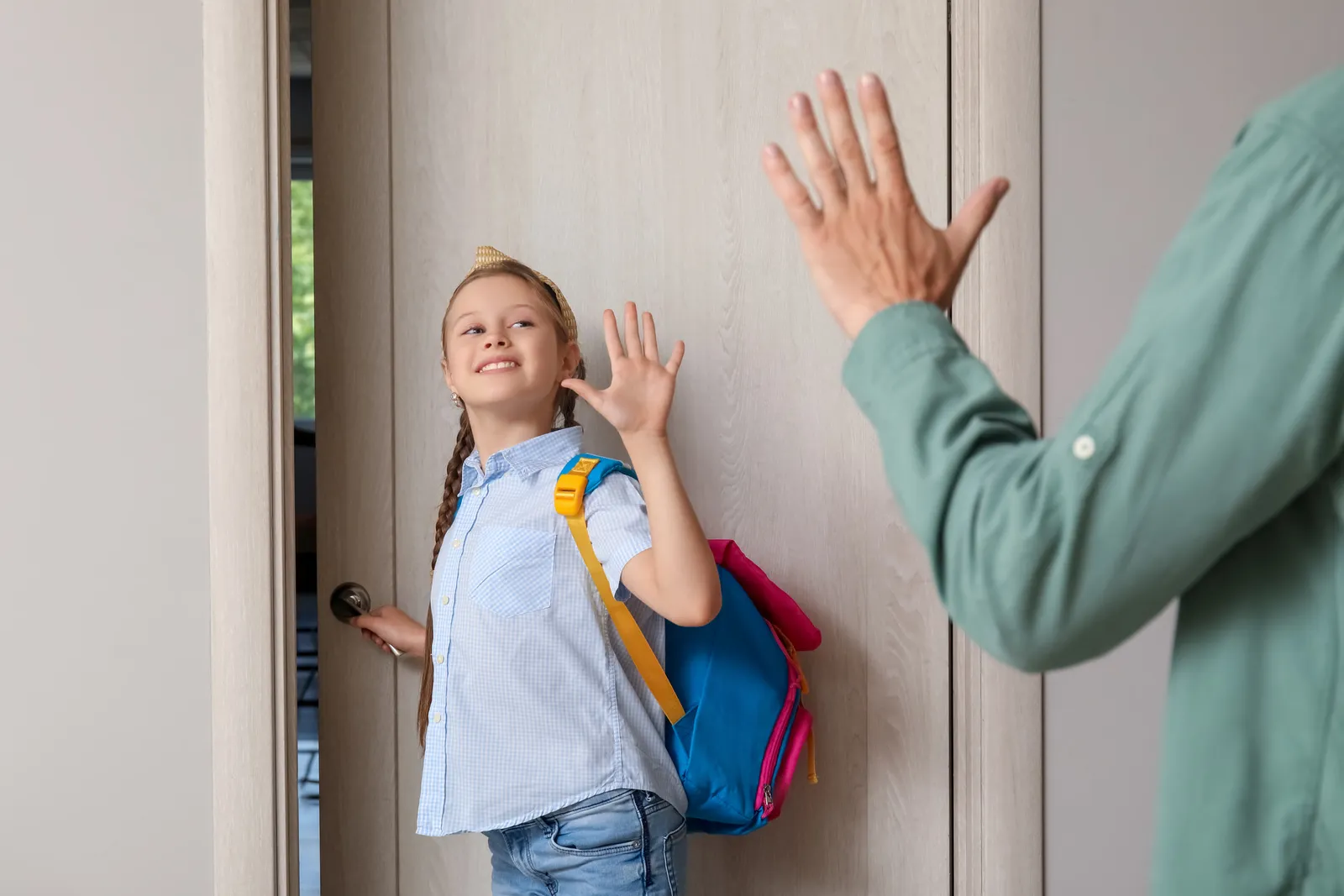 A little girl saying goodbye to her father in a hallway before school