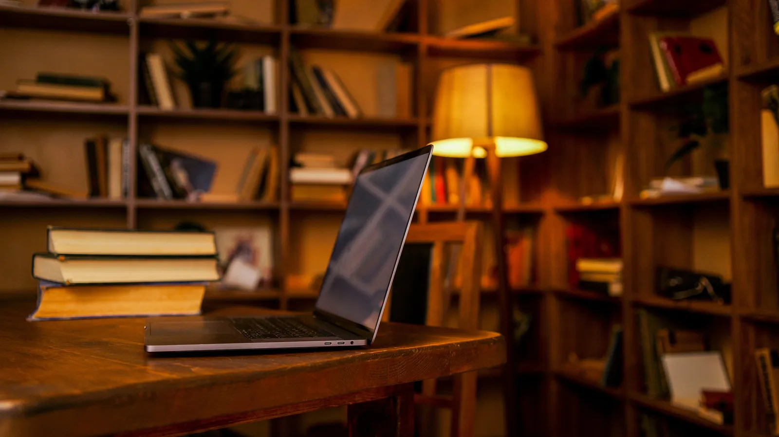 Books and a laptop on a desk in warm, cozy lighting